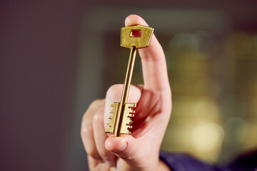  Close up of human hand holding golden key