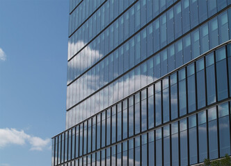 Fototapeta na wymiar Tight Shot Of Glass Building Reflecting White Clouds Blue Sky