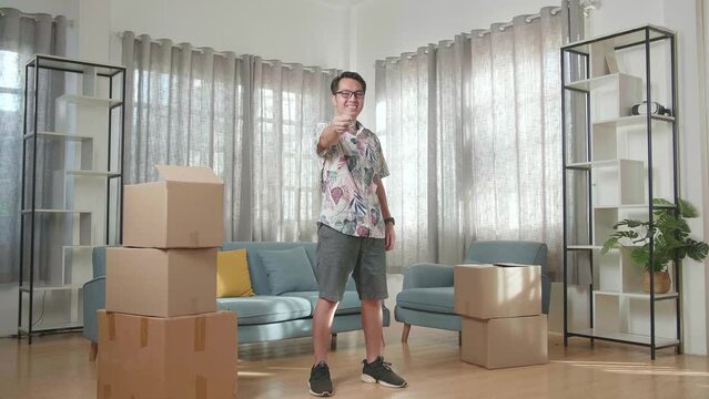 Asian Man With Cardboard Boxes Smiling And Showing The Keys To Camera In The New House

