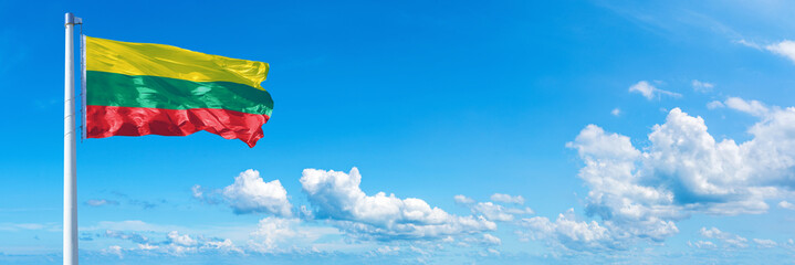 Lithuania flag waving on a blue sky in beautiful clouds - Horizontal banner - obrazy, fototapety, plakaty