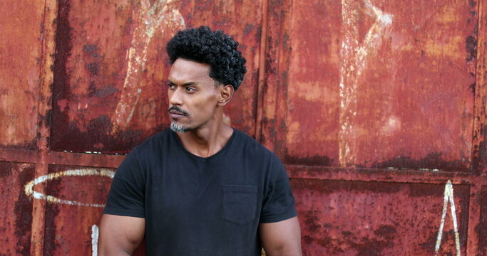 Bad boy African man crossing arms staring at camera in urban grunge background