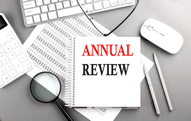 ANNUAL REVIEW text on notepad on chart with keyboard and calculator on grey background