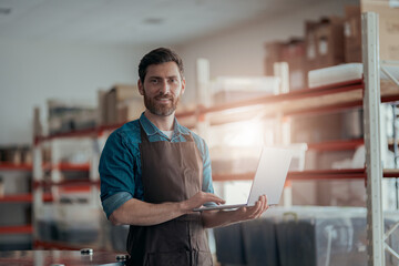 Male worker working laptop on background of warehouse 