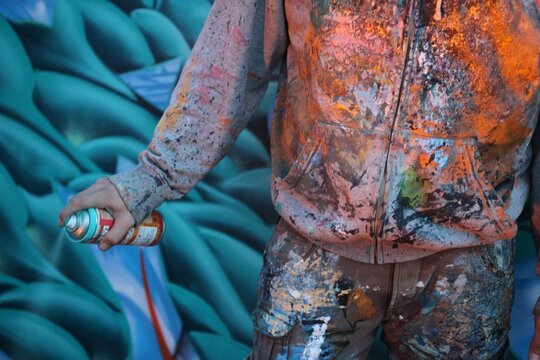 Graffiti artist in front of graffiti wall