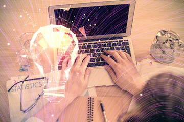 Double exposure of man's hands typing over computer keyboard and bulb hologram drawing. Top view. Idea concept.