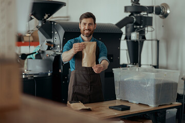 Business owner propose roasted coffee beans in paper bag in coffee factory ready for sale