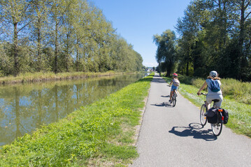 maman et sa fille en train de faire du vélo sur une piste cyclable le long d'un canal en été