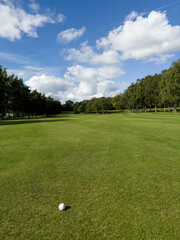 Flag and the hole at golf club blue sky summers day with some clouds