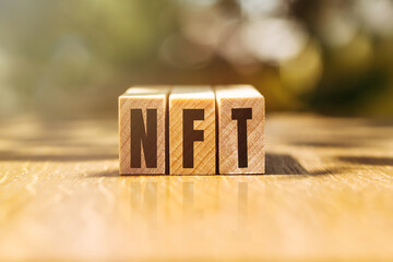 Concept word NFT on wooden cubes on wooden background. Inscription on a financial, business or economic theme. NFT - short for Non-Fungible Token