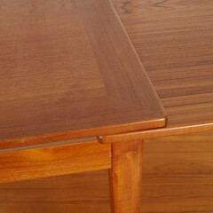 Corner detail of a vintage wood Danish Teak Draw Leaf Dining Table