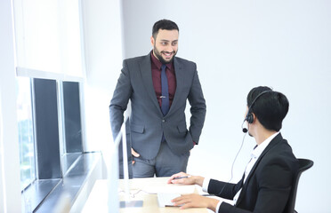  Happy attractive business people. Call center worker accompanied by team. Smiling customer support operator at work. Young employee working with a headset. Successful business professionals.