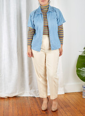 Product photograph Wool Outer Pleated High Waist Trousers in Cream and vintage denim zipper tee over colorful 1970s rainbow turtleneck shirt in front of white wall and curtains.