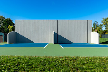 Example of an outside American Handball courts with concrete wall, located at a park or school.
