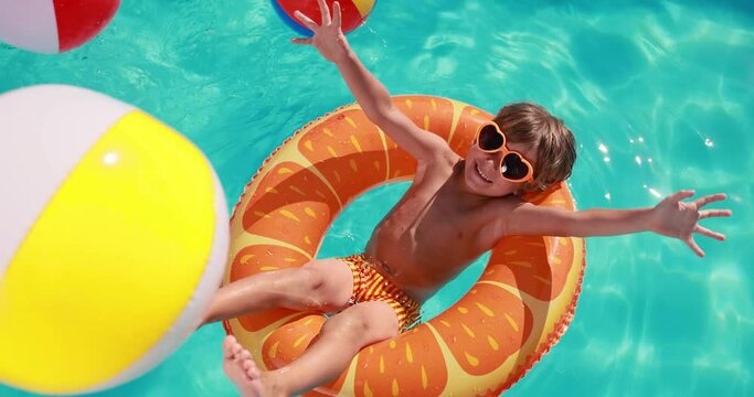 Happy child having fun on summer vacation. Kid playing in swimming pool. Active healthy lifestyle concept. Slow motion