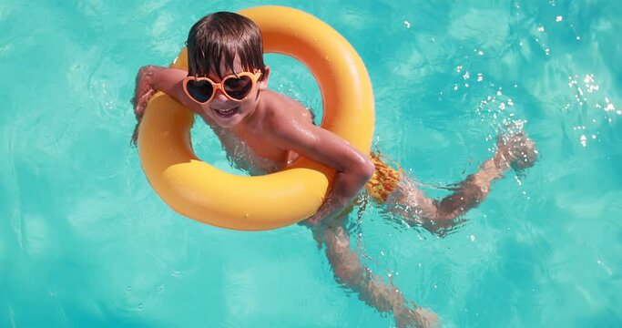 Happy child having fun on summer vacation. Kid playing in swimming pool. Active healthy lifestyle concept. Slow motion