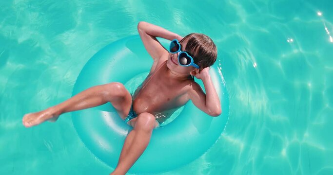 Happy child having fun on summer vacation. Kid playing in swimming pool. Top view portrait of funny boy. Active healthy lifestyle concept. Slow motion