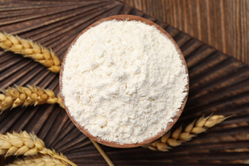 Bowl of organic wheat flour on wooden table, flat lay