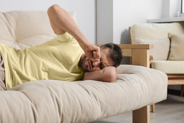 Obraz na płótnie Canvas Sleepy man lying on sofa at home