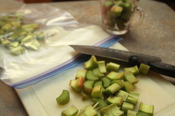 Chopped rhubarb, knife, measuring cup and pastic bag for freezing