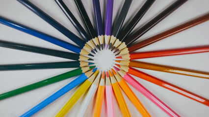 Many colored pencils are arranged around the edges of the image as a frame. In the center is an empty background with space for text. Mock up with copy space.