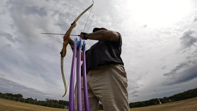 An archer shoots multiple arrows in a row at an archery range.