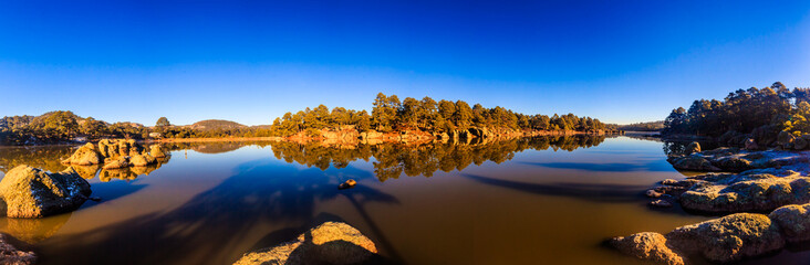 panoramic of lake at morning with blue sky and forest around in arareco lake, creel chihuahua 