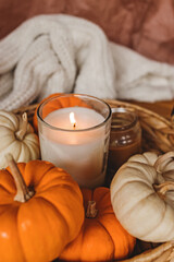 Fototapeta na wymiar Cozy fall still life composition with decorative pumpkins and burning candle.