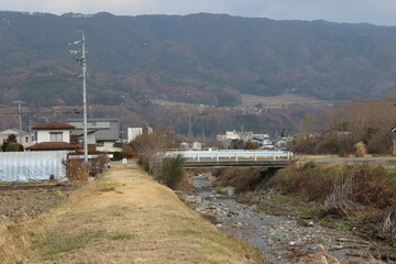 small road bridge over river in front of mountains