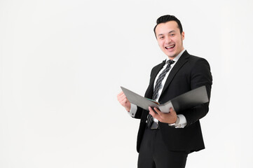 Naklejka na ściany i meble Young Asian man holding a folder, wearing a black suit, and celebrating victory isolated on white background.