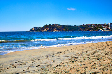 beach at sunny day with blue sea and coast in the background in puerto escondido oaxaca