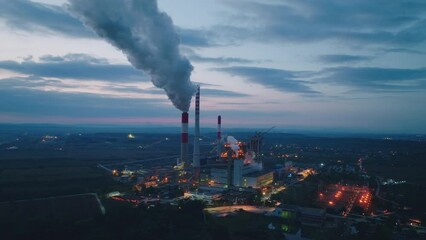 Factory emissions from smokestacks backlit in the sunrise.