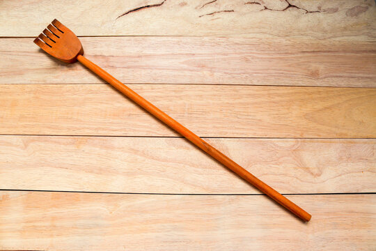 Wooden back scratcher for back scratching itchy time on wooden background closeup.