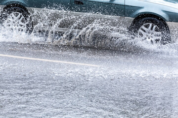 car driving in heavy rain on flooded road. splash of water from car wheels.