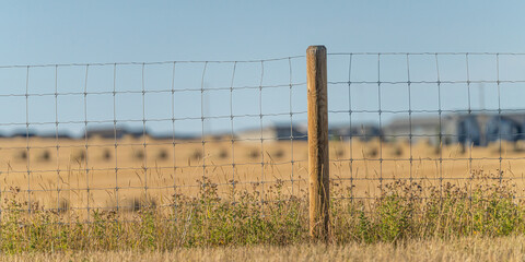 wire fence with farm fields behind it