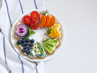 Rainbow sandwiches heart shape on white table. Breakfast bread rainbow sandwiches with colorful vegetables. Love, Valentines day food and LGBT pride flag concept. Copy space. Top view. Healthy food.