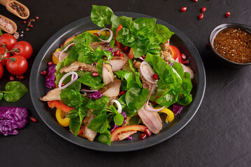 Grilled steak with fresh vegetable, sweet pepper, tomatoes, red onion, pink pepper and spices. Home made tasty food. Concept for tasty and healthy meal. Black stone background. Pork steak with salad