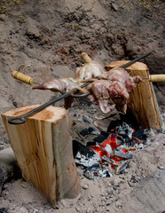 conejos asados a las brasas de carbon en un asador pequeño montado en troncos