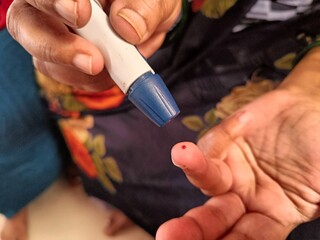 Diabetic patient takes blood sample for checking sugar level.