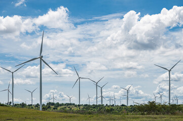 Electricity generating white large wind turbine standing against blue sky background in a windy zone area in southeast Asia.