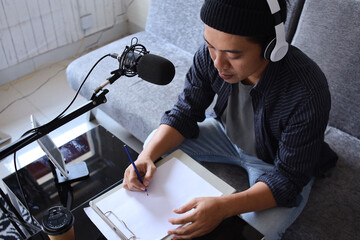 Asian man radio program host or blogger in headphones recording audio podcast using professional...