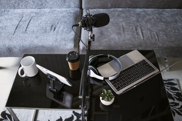 Home studio podcast interior. Microphone, laptop and headphone on the table