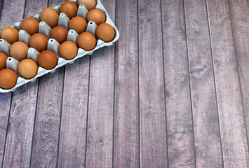 Brown eggs in an egg box on a wooden background.