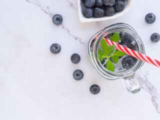 Infused water with fresh organic blueberries and drinking straw on marble background. Space for your text. Top view, flat lay..