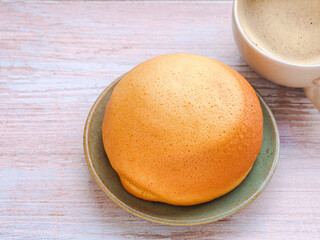 Homemade mexican vanilla bun (coffee bun) on turquoise clay round plate and coffee cup over rustic...