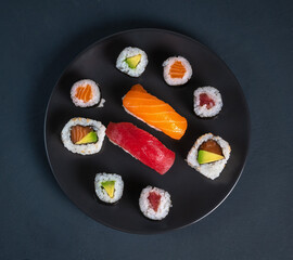 Top view of a plate of maki sushi on dark background