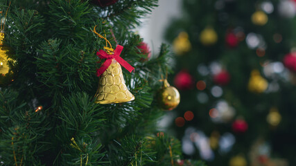 Cute golden vivid bell hang on traditional Christmas tree as beautiful ornament decoration for wonderful home party of new year celebration on winter night.