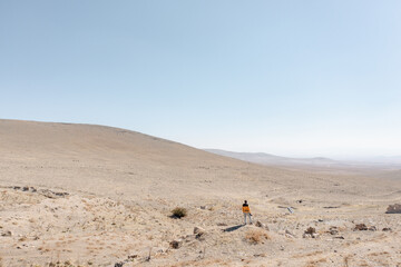 Young man photographer from behind standing and looking at steppe, dry lands. Concept for climate change, global warming