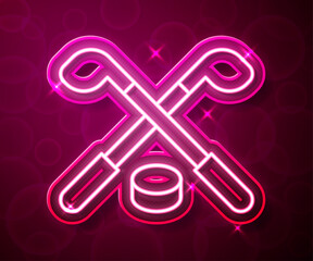 Glowing neon line Ice hockey sticks and puck icon isolated on red background. Game start. Vector