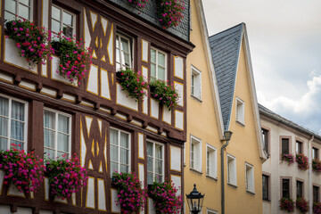 Fototapeta na wymiar Fasaden von alten Häusern teilweise mit Fachwerk und Blumen an den Fenstern - eine typische Altstadtszene