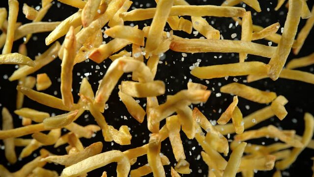 Super Slow Motion Shot of French Fries and Salt Flying Towards Camera Isolated on Black at 1000fps.
